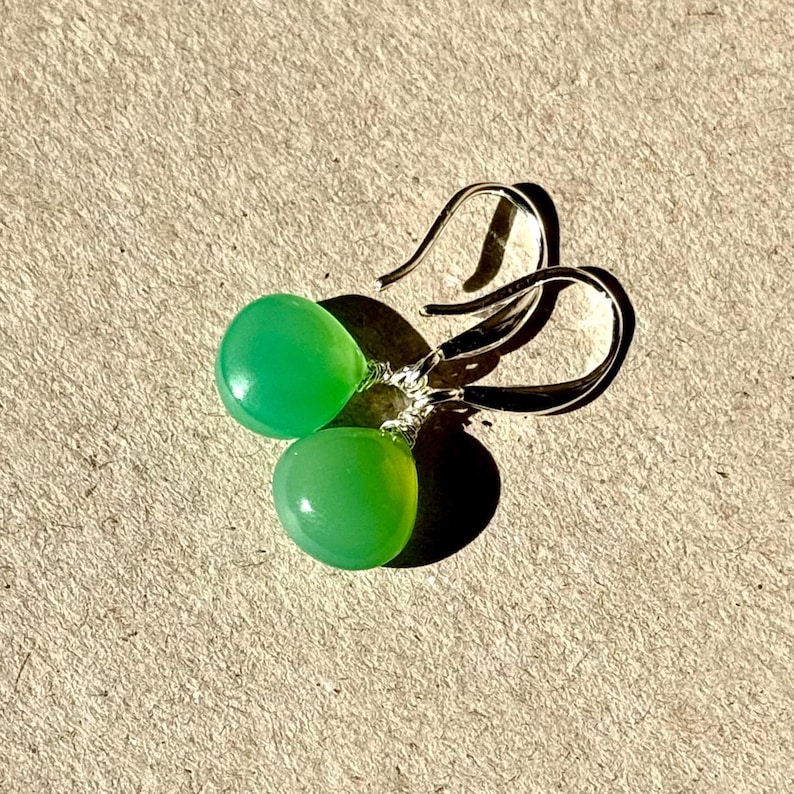 May include: A pair of silver dangle earrings with green gemstone drops.