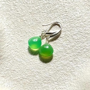 May include: A pair of silver earrings with green gemstone drops. The earrings are teardrop shaped and have a simple design.