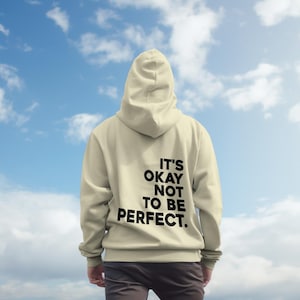 以下が含まれることがあります： 背面に「It's okay not to be perfect.」という黒いプリントが施されたベージュのパーカー