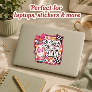 May include: A colorful sticker featuring a can of "Alani Energy" with the text "Suspect Runs on Alani." The design includes a pink bow, checkered flags, and star accents. The sticker is placed on a laptop.
