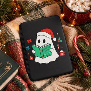 K&ouml;nnte beinhalten: Schwarze Tablet-H&uuml;lle mit einem Cartoon-Geist, der einen Weihnachtsmannhut tr&auml;gt und ein gr&uuml;nes Buch mit "Christmas Cheer" liest. Festliche Weihnachtsdekorationen: Zuckerstange, Becher und Ornamente.