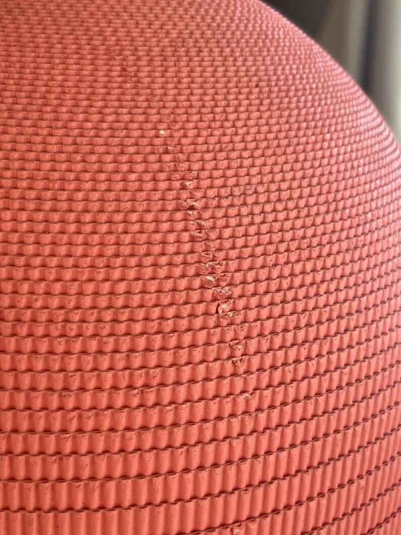 May include: Close-up of a red, textured, rubber ball. The ball has a repeating pattern of small, raised circles.