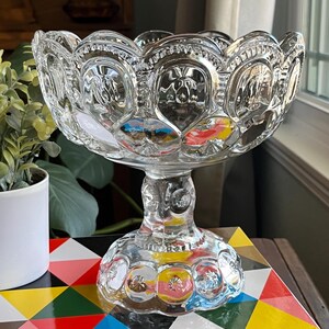Op de afbeelding: Een glazen kom met een gegolfde rand en een voet. De kom heeft een patroon van kleine cirkels en sterren.