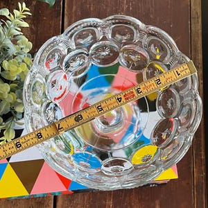 Op de afbeelding: Een glazen kom met een gegolfde rand en een reli&euml;fpatroon van kleine cirkels. De kom is ongeveer 18 cm in diameter.