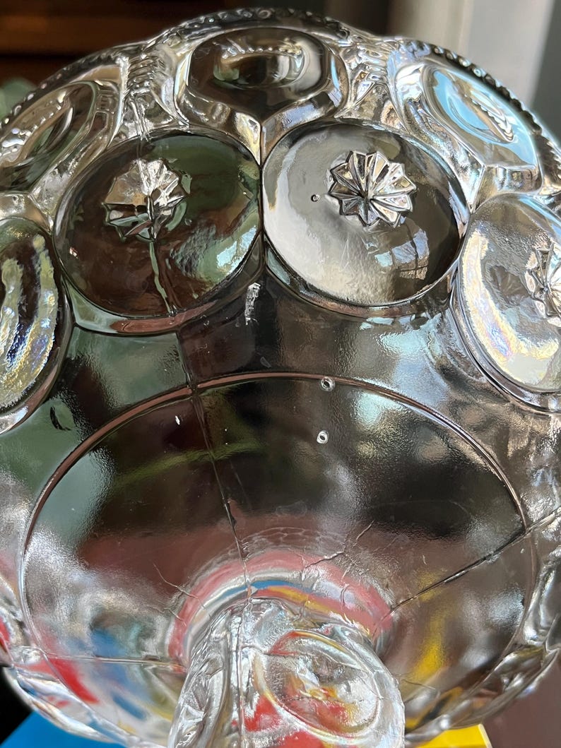 Op de afbeelding: Een glazen snoepschotel met een gegolfde rand en een reli&euml;f van cirkels en sterren. De schotel heeft een voet.