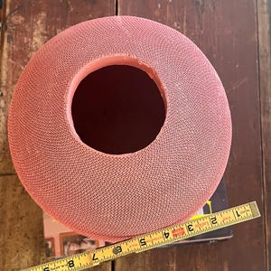 May include: A large, pink, round vase with a textured surface and a wide opening at the top. The vase is approximately 7 inches in diameter.