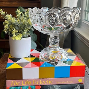 Op de afbeelding: Een heldere glazen voetkom met een gegolfde rand en een stervormig patroon. De kom staat op twee boeken, een met de titel "The Life Eclectic" en de andere met de titel "modernstarts".