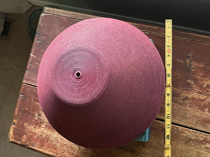 May include: A large, round, burgundy-colored bowl with a textured surface. The bowl is approximately 13 inches in diameter.