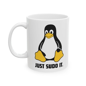 Puede incluir: Una taza de cerámica blanca con un gráfico de un pingüino negro y blanco con pico y patas amarillas. Debajo del pingüino, el texto "JUST SUDO IT." está impreso en letras mayúsculas negras y negritas. La taza tiene un asa curva a la izquierda.