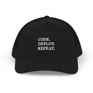 May include: A black trucker hat featuring a structured front panel and a mesh back. The front of the cap displays the white embroidered text "CODE. DEPLOY. REPEAT." in a clean, sans-serif font, centered above the curved brim of the hat.