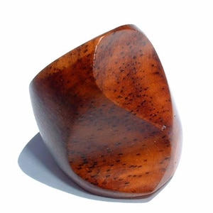 May include: A wooden ring with a unique, asymmetrical design. The ring is made of dark brown wood with a natural grain pattern.