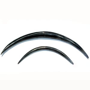 May include: Two curved, dark gray surgical needles of different sizes are displayed against a white background. The needles have a smooth, metallic appearance and a sharp point at each end. The larger needle is approximately 4 inches long, while the smaller one is about 2 inches.