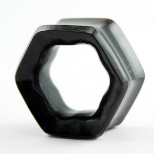 May include: Black hexagonal shaped ear gauge plug. The plug has a smooth, polished finish.