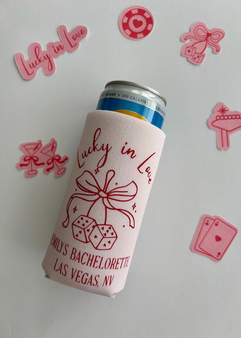 Pode incluir: Resfriador de latas rosa com o texto "Lucky in Love" e uma fita vermelha com dados e cora&ccedil;&otilde;es. O texto "Emily's Bachelorette Las Vegas, NV" est&aacute; impresso abaixo do design.
