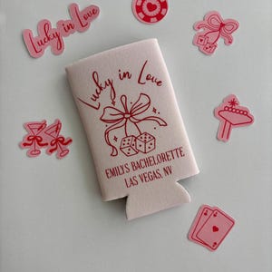 Pode incluir: Frigideira branca com um design vermelho que diz "Lucky in Love" e "Emily's Bachelorette Las Vegas, NV". O design tamb&eacute;m inclui um la&ccedil;o vermelho, dados e uma estrela.