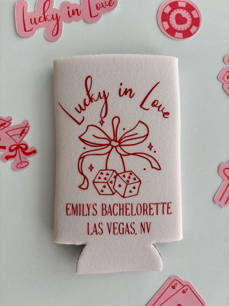 Pode incluir: Resfriador de latas rosa com um design vermelho que diz "Lucky in Love" com um la&ccedil;o e dados. O texto "Emily's Bachelorette Las Vegas, NV" est&aacute; impresso abaixo do design.
