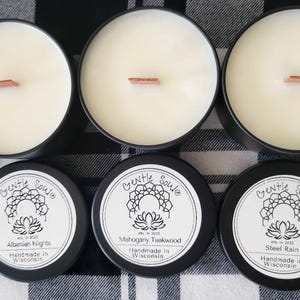 May include: Six black candle jars with white labels. The labels have a black and white mandala design and the text "Gentle Soule" in a script font. The candle scents are "Albanian Nights", "Mahogany Teakwood", and "Steel Rain".