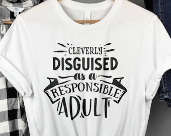 Puede incluir: Camiseta blanca con texto negro que dice "Cleverly Disguised as a Responsible Adult".