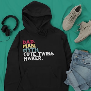 May include: Black hooded sweatshirt with the text "DAD. MAN. MYTH. CUTE TWINS MAKER." in colorful retro font.