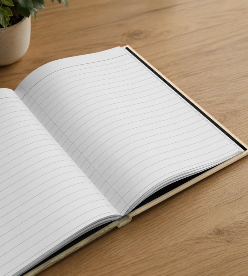 May include: An open notebook with white pages featuring black horizontal lines. The notebook has a light-colored cover and is positioned at an angle, revealing the interior paper layout with clear, evenly spaced ruled lines for writing.