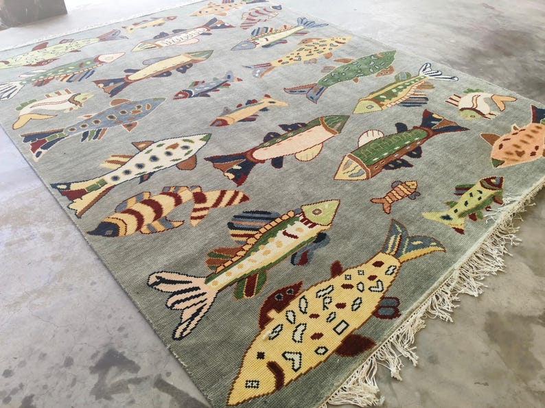 May include: A rectangular rug with a pale grey backdrop, patterned with colourful fish. The fish designs vary in size and colour, including yellow, green, blue, and brown. The rug has a fringed edge, and is suitable for a living room.