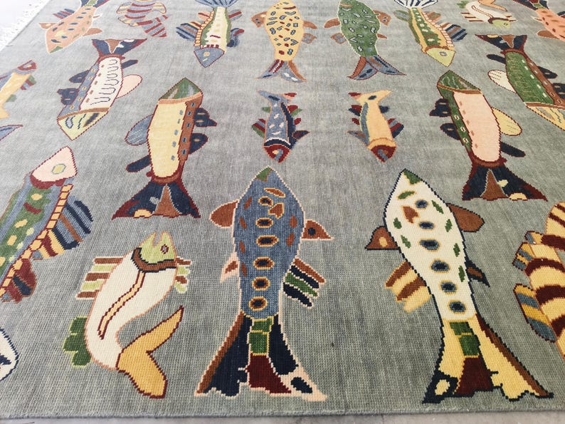 May include: A light blue rug featuring a repeating pattern of colourful fish. The fish are in various colours, including yellow, blue, green, and brown. The rug is a decorative item.