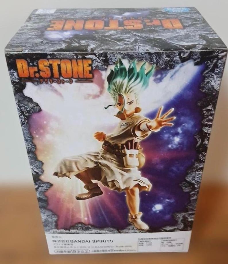 May include: A box featuring a vibrant illustration of a character from the anime series Dr. Stone. The character has green hair and is wearing a light-colored outfit. The box has the Dr. Stone logo and Japanese text.