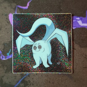 May include: A blue and white cartoon creature with large eyes and a long tail. The creature is on a black background with glitter.