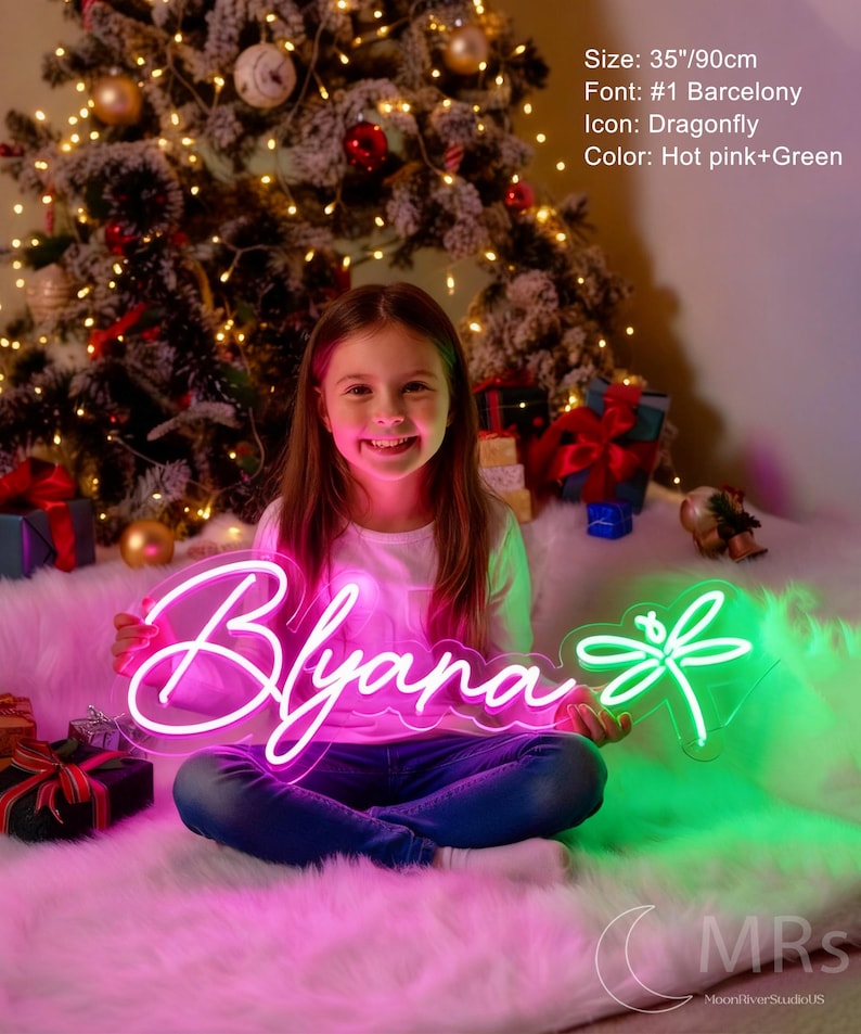 Puede incluir: Un letrero de ne&oacute;n personalizado con el nombre Blyana en letras cursivas de color rosa intenso y un icono de lib&eacute;lula verde. El letrero mide 90 cm de ancho. El texto en la imagen especifica: Size: 35"/90cm, Font: #1 Barcelony, Icon: Dragonfly, Color: Hot pink+Green.