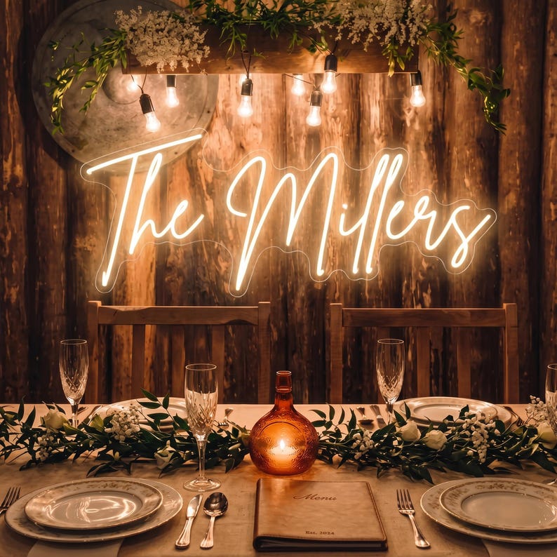Puede incluir: Una mesa de recepci&oacute;n de boda con un letrero de ne&oacute;n que dice "The Millers". La mesa est&aacute; puesta con platos, cubiertos y vasos. Una vela en una botella de vidrio decorativa se encuentra en el centro. El fondo es una pared de madera.