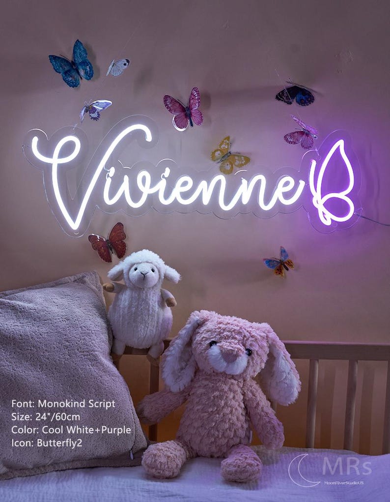 Puede incluir: Un letrero de ne&oacute;n en color blanco fr&iacute;o y morado que muestra el nombre Vivienne en fuente Monokind Script con un icono de mariposa, midiendo 60 cm de ancho. El letrero est&aacute; montado en una pared decorada con varias pegatinas de mariposas.