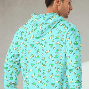 May include: A light blue hoodie with a pattern of small, colorful geometric shapes. The hoodie has a drawstring hood and a kangaroo pocket.