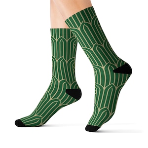 May include: Green and beige patterned socks with a geometric design. The socks are shown on a model's feet.
