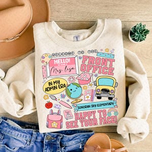 May include: A beige sweatshirt with a colorful graphic design featuring the text "Welcome to the Front Office", "Hello! My name is Mrs. Lisa", "In my Admin Era", "Sonoran Sky Elementary", and "Happy to see your face!"