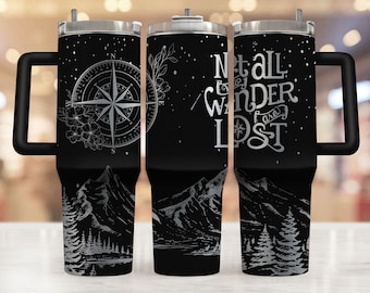 May include: A black stainless steel tumbler with a white design featuring a compass, mountains, and the text "Not all who wander are lost".