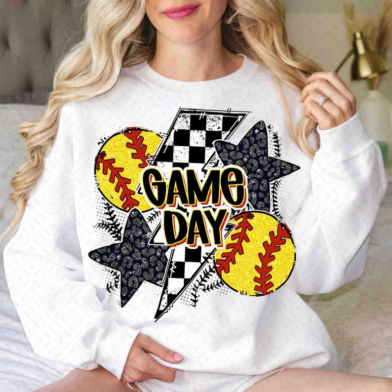 Może przedstawiać: Biała bluza z nadrukiem graficznym przedstawiającym wz&oacute;r w kratkę, błyskawicę, dwa wzory piłek miękkich i tekst "GAME DAY".