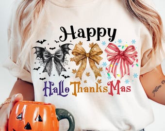 May include: A white t-shirt with the text "Happy Hallo Thanks Mas" in colourful letters. The shirt features a black bat with a bow, a brown bow with autumn leaves, and a red and white striped bow with a bell.