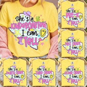 May include: A bright yellow t-shirt featuring a graphic of the state of Texas with blue horizontal lines. The design includes a pink cowboy hat, a yellow star, a pencil, a smiley face, and pink cowboy boots, with the text She's a grade I can Tell.