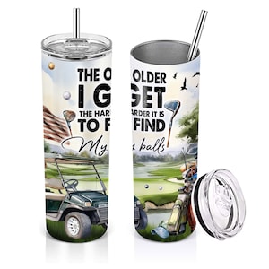 May include: A stainless steel tumbler with a golf-themed design. The tumbler features a green golf course with a golf cart, golf clubs, and golf balls. The text on the tumbler reads "The older I get the harder it is to find my balls".