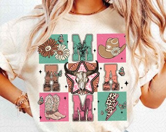 Puede incluir: Una camiseta blanca con un diseño gráfico que presenta la palabra "MOM" en un estilo retro. El diseño incluye una calavera, un sombrero de vaquero, botas, un cactus y un rayo.