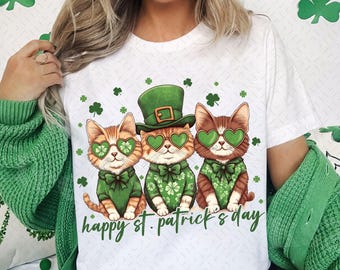 May include: White t-shirt with a graphic of three cats wearing green shamrock glasses and hats. The text "happy st. patrick's day" is printed below the cats.