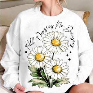 May include: White sweatshirt with a graphic of three white daisies and the text "All Daisies No Dosies".
