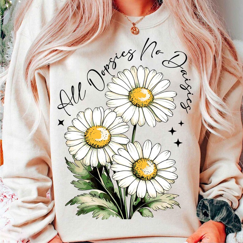 May include: A cream-coloured sweatshirt with the text "All Daisies No Worries" in black lettering. The text is surrounded by three white daisies with yellow centres and green leaves.