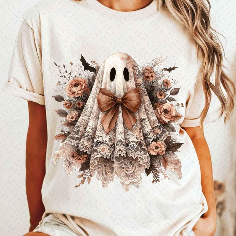 以下が含まれることがあります： レースのベールと茶色のリボンをつけた幽霊が描かれた白いTシャツ。幽霊は茶色の花と葉に囲まれている。