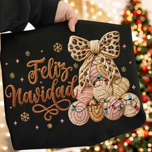 Puede incluir: Cojín negro con temática navideña con diseño bordado. Presenta un lazo con estampado de leopardo, un árbol hecho de círculos tejidos y el texto "Feliz Navidad" en letras estilo cuerda. Acentuado con copos de nieve y estrellas.