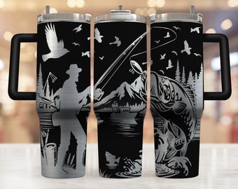 May include: A stainless steel tumbler with a black background featuring a fishing theme. The design includes a fisherman, mountains, a lake, fish, birds, and fishing gear. The tumbler has a black handle and a silver lid.
