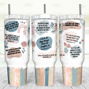 K&ouml;nnte beinhalten: Ein wei&szlig;er Becher mit Henkel und Strohhalm. Der Becher hat ein rosafarbenes, blaues und goldenes Design mit floralen Akzenten und inspirierenden Zitaten. Die Zitate beinhalten "Gott ist unsere Zuflucht und St&auml;rke, immer bereit, uns in Zeiten der Not zu helfen", "Freue dich am Herrn, und er wird dir die W&uuml;nsche deines Herzens erf&uuml;llen", "Als Zweifel meinen Geist erf&uuml;llten, gab mir dein Trost erneute Hoffnung und Freude", "Wir tun dies, indem wir unsere Augen auf Jesus richten, den Meister, der unsere Treue beginnt und vollendet", "Ich kann alles durch Christus, der mich st&auml;rkt", "Ich strecke mich nach dem Ziel aus, um den Preis zu gewinnen", "Seid also wahrhaft fr&ouml;hlich. Es gibt eine wunderbare Freude, die vor euch liegt...", "Denn ich kann alles durch Christus, der mir Kraft gibt", und "So laufe ich mit Zielstrebigkeit in jedem Schritt. Ich bin nicht nur am Schattenboxen".
