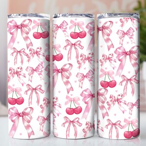 May include: Three stainless steel tumblers with a white background and a pink and white cherry and bow pattern.