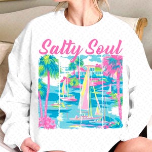 May include: White sweatshirt with a pink graphic of palm trees, sailboats, and the text "Salty Soul".