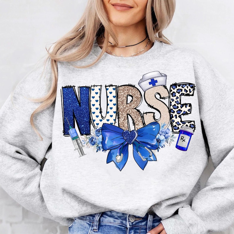 May include: A gray sweatshirt with the word "NURSE" in blue, gold, and white glitter letters. The letters are decorated with blue hearts, a blue bow, a blue and white syringe, a blue and white pill bottle, and a white nurse's hat with a blue cross.